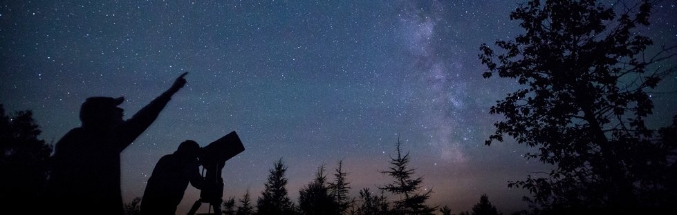 Two individuals with a telescope looking at the stars